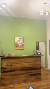 Wooden reception desk with Thai artwork and a green feature wall at Arokaya Wellness Spa Thai massage in St Kilda