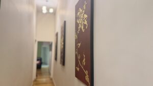Hallway with a gold Thai floral art panel on a burgundy wall at Arokaya Wellness Spa Thai massage St Kilda