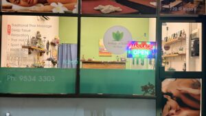 Shopfront window with massage service list and neon open sign at Arokaya Wellness Spa Thai massage St Kilda